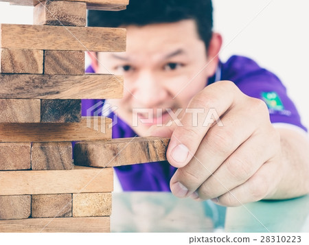 Asian guy is playing a wood blocks tower game Asian guy is playing a wood blocks tower game 28310223