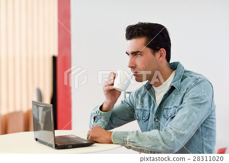 Good looking man wearing denim shirt sitting in a coffee bar Good looking man wearing denim shirt sitting in a coffee bar 28311020