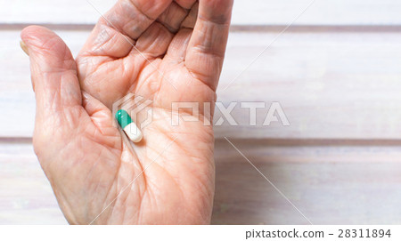Senior hand holding medical capsule 28311894