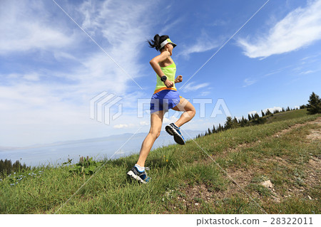 young woman trail runner running on mountain peak 28322011