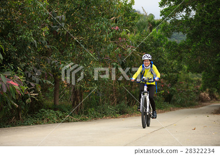 young woman riding mountain bike on forest trail 28322234