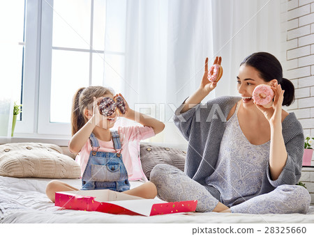 Mother and her daughter eating donuts Mother and her daughter eating donuts 28325660