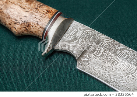 Hunting damascus steel knife on a green fabric 28326564