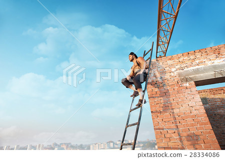 Builder with bare torso sitting on ladder. 28334086