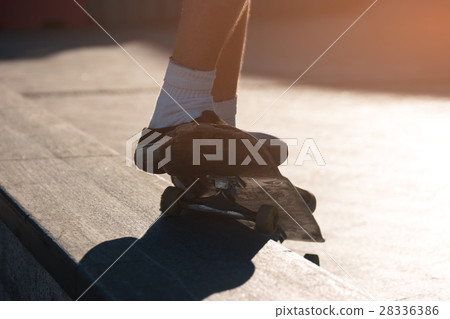 Feet standing on a skateboard. 28336386