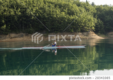 A Young single scull rowing competitor paddles on A Young single scull rowing competitor paddles on 28341085