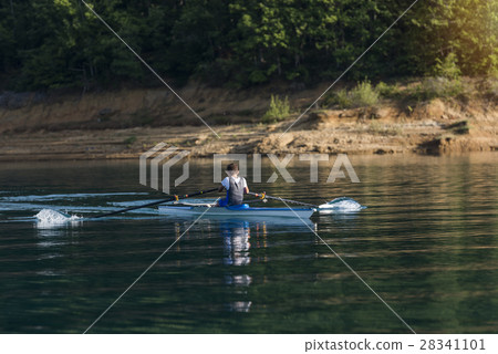 A Young single scull rowing competitor paddles on A Young single scull rowing competitor paddles on 28341101