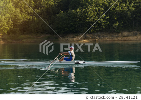 A Young single scull rowing competitor paddles on A Young single scull rowing competitor paddles on 28341121