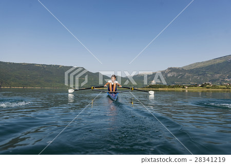 A Young single scull rowing competitor paddles on A Young single scull rowing competitor paddles on 28341219
