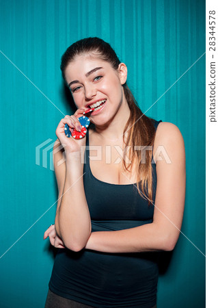 Young girl holding poker chips on blue background 28344578