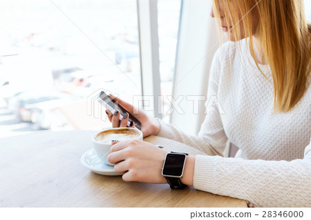 Girl with watch holding mobile phone Girl with watch holding mobile phone 28346000