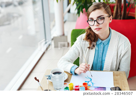 Girl with glasses sitting with colorful paints 28346507