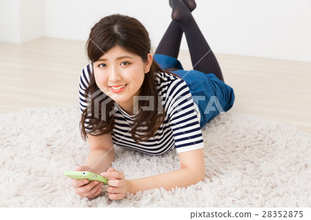 看智能手機的婦女在屋子裡 看智能手機的婦女在屋子裡 28352875