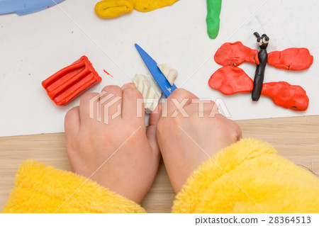 The child cuts off a piece of plasticine stack, close-up The child cuts off a piece of plasticine stack, close-up 28364513
