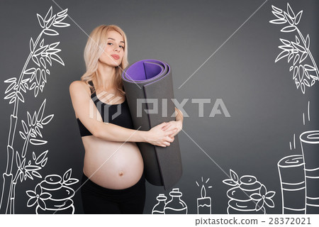 Pleasant young pregnant woman holding sport rug Pleasant young pregnant woman holding sport rug 28372021