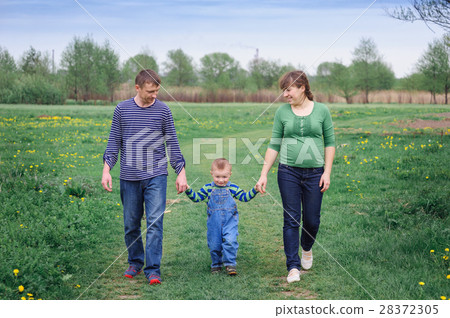 young family and young son walk on a spring meadow 28372305