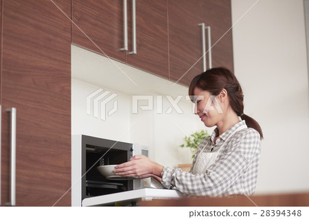 Women who stand in the kitchen and use a microwave 28394348