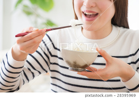 A young woman holding a cup and eating rice A young woman holding a cup and eating rice 28395969