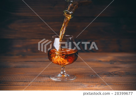Pouring brandy or cognac from the bottle into  28399677
