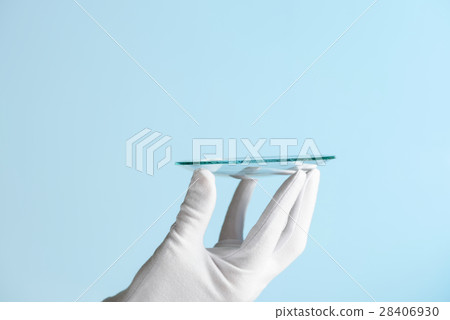 Scientist hand in glove show circle piece of new research prototype of transparent clear glass or plastic material 28406930