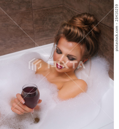 Girl is drinking wine in bathtub with foam. Girl is drinking wine in bathtub with foam. 28410259