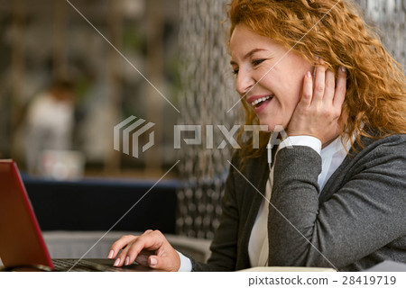 Cheerful pleasant woman using laptop in the cafe 28419719