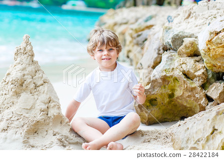 Little kid boy building sand castle on tropical 28422184