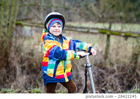 Cute preschool kid boy riding on scooter in park 28422245