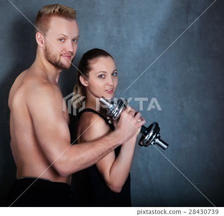 Athletic couple with a dumbells near the wall Athletic couple with a dumbells near the wall 28430739