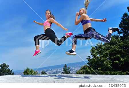 Two happiness young women jumping over blue sky Two happiness young women jumping over blue sky 28432023