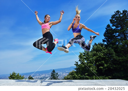Two happiness young women jumping over blue sky Two happiness young women jumping over blue sky 28432025