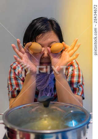 Asia woman cooking by put a flesh egg in to a hot pot Asia woman cooking by put a flesh egg in to a hot pot 28434672