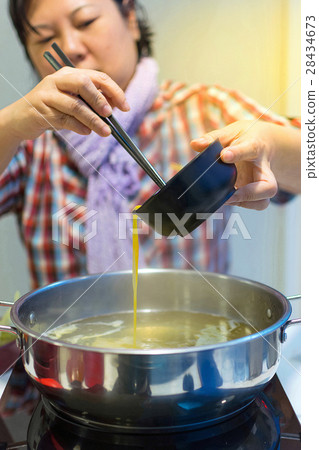 Asia woman cooking by put a flesh egg in to a hot pot 28434673