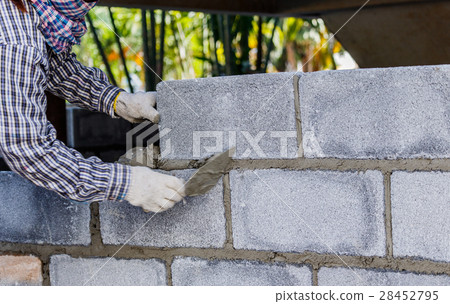 Bricklayer putting down row of bricks Bricklayer putting down row of bricks 28452795