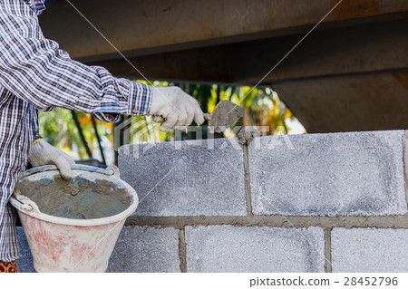 Bricklayer putting down row of bricks Bricklayer putting down row of bricks 28452796