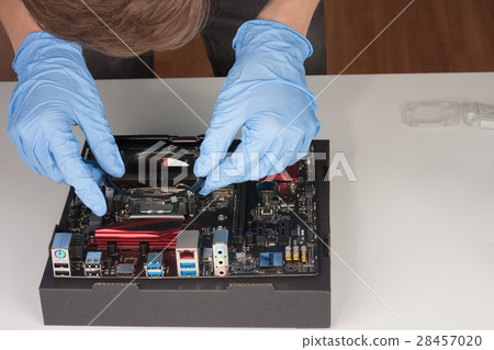 Young man with gloves installing part of CPU cooler fan. 28457020