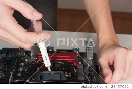 Close up of man hands with syringe applying thermal paste on the Close up of man hands with syringe applying thermal paste on the 28457021