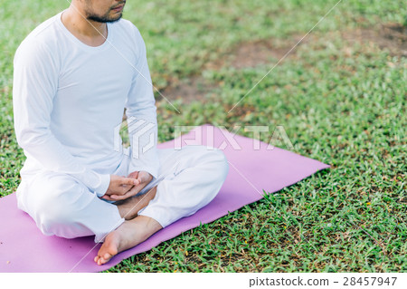 Asian man meditating on green grass in the park 28457947