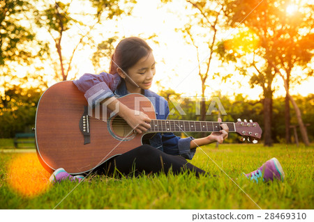 Young artist play solo guitar in green nature park 28469310
