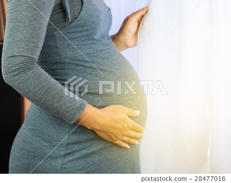 Pregnant Woman standing at window in a sunny day. 28477016