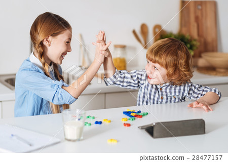 Lively positive siblings giving a high five Lively positive siblings giving a high five 28477157