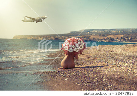 Beautiful naked girl lying on the beach under an u 28477952