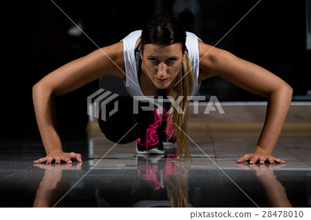 woman in a gym exercising, doing push ups. Dark woman in a gym exercising, doing push ups. Dark 28478010