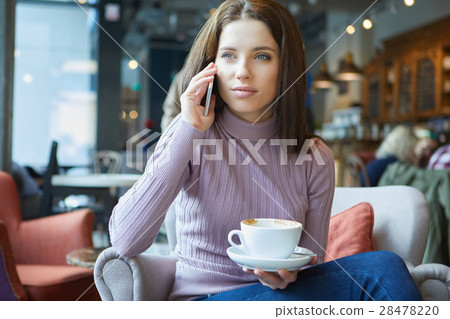 Image of young female reading sms on the phone in cafe 28478220