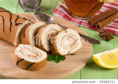 Biscuit swiss roll with a cup of tea on green Biscuit swiss roll with a cup of tea on green 28482211