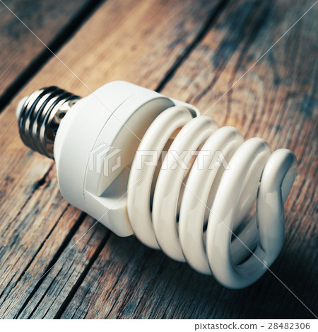 Energy saving light bulb on wooden desk Energy saving light bulb on wooden desk 28482306