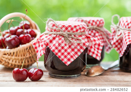 Jars of jam and basket with cherry. 28482652