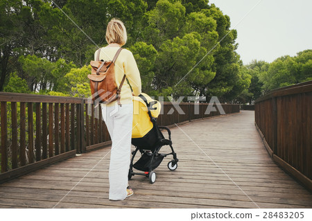 Young mother strolling with carriage in park 28483205