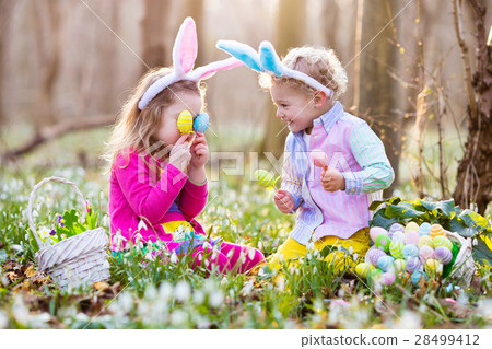 Kids on Easter egg hunt in blooming spring garden 28499412