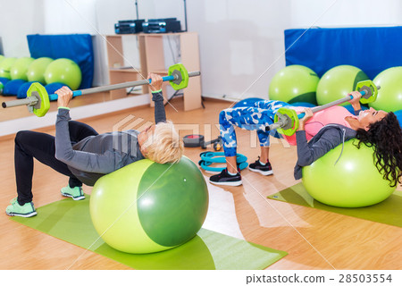 Two slim women exercising with barbell and Swiss 28503554